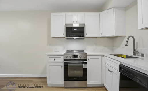 A kitchen with white cabinets and appliances.